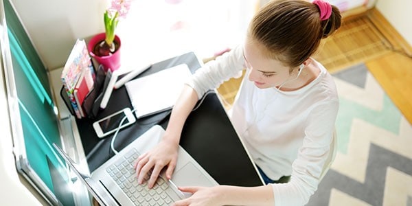 Preteen Schoolgirl Doing Her Homework With Laptop Computer At Ho
